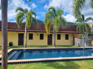 a swimming pool in front of a house with palm trees at AoNang 3 Monkeys Pool Resort in Ao Nang Beach