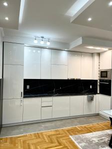 eine Küche mit weißen Schränken und schwarzen Arbeitsplatten in der Unterkunft Apartman Central in Banja Luka
