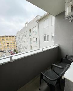 2 Stühle auf einem Balkon mit Blick auf ein Gebäude in der Unterkunft Apartman Central in Banja Luka