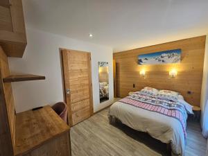een slaapkamer met een bed en een houten muur bij Hôtel Plein Soleil in Vacheresse