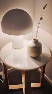 een tafel met een lamp en een vaas erop bij Ralph's Little Cottage in Christchurch
