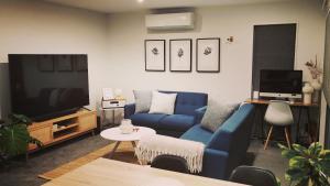 een woonkamer met een blauwe bank en een tv bij Ralph's Little Cottage in Christchurch