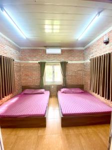 two beds in a room with pink sheets at Lều biệt thự in Hanoi