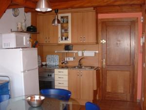 レスカラにあるApartamentos Olimpiaのキッチン(木製キャビネット、白い冷蔵庫付)