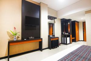 a hotel room with a bed and a flat screen tv at Parkside Mandarin Hotel Pekalongan in Pekalongan
