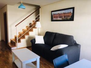 a living room with a black couch and stairs at Dúplex Palacio de los Momos in Zamora