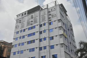 a tall white building with blue windows at Hotel Grand Akther Sylhet in Sylhet