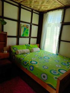 a bedroom with a green bed with a window at FrancoEly's A Family Camp in Daliao