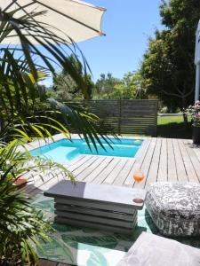 a swimming pool with a wooden deck and an umbrella at Lush Spacious Family Home between Beach & Town in Knysna