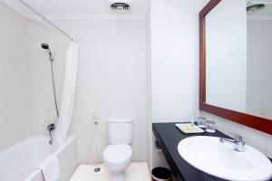 a bathroom with a sink and a toilet and a mirror at Parkside Mandarin Hotel Pekalongan in Pekalongan
