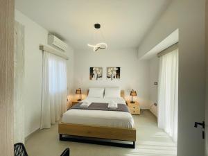 a white bedroom with a bed and two windows at Villa Rodelia 1 in Roda