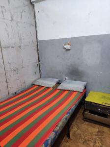 een bed in een kamer met een kleurrijke gestreepte deken bij New Star Lodge in Colombo