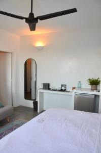 Royal-Ma Resort في Perástra: غرفة نوم بسرير أبيض ومروحة سقف