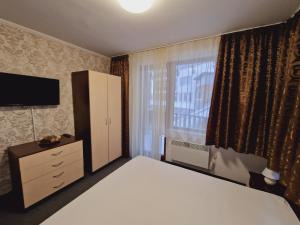 1 dormitorio con 1 cama, vestidor y ventana en апартаменти Уют Гранд Манастира, en Pamporovo