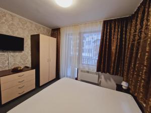 1 dormitorio con 1 cama, vestidor y ventana en апартаменти Уют Гранд Манастира, en Pamporovo