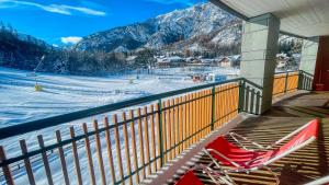 einen roten Stuhl auf einem Balkon mit Bergblick in der Unterkunft Appartamento Smith Alta Langa - Affitti Brevi Italia in Bardonecchia