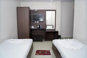 a hotel room with two beds and a television at Sonar Bangla Guest House in Kolkata