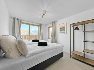 1 dormitorio con 1 cama con sábanas blancas y ventana en The Laughing Cow - 10 mns from Sion and ski, en Ayent