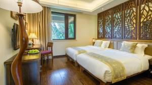 Sanya Yalong Bay Villas & Spa في سانيا: غرفة نوم بسريرين ومكتب فيه تلفزيون