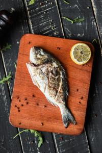 a fish on a cutting board with a lemon at Hôtel Restaurant Gites Kribi in Kribi