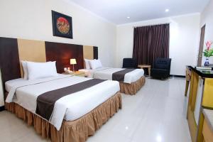 a hotel room with two beds and a television at Parkside Mandarin Hotel Pekalongan in Pekalongan