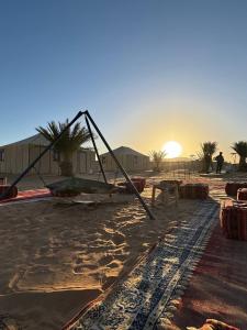 a large object on the beach with the sunset in the background at Nomads Luxury Camp Merzouga in Adrouine