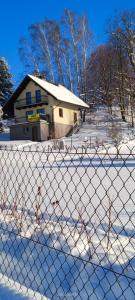 a fence in front of a house in the snow at Domek pod Lipą in Korbielów