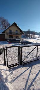 a fence in the snow in front of a house at Domek pod Lipą in Korbielów