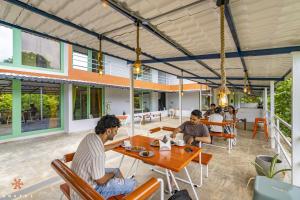 eine Gruppe von Menschen, die an einem Tisch in einem Restaurant sitzen in der Unterkunft Zostel Pondicherry, Auroville Road in Puducherry