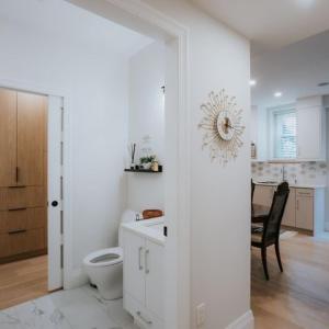 a white bathroom with a toilet and a dining room at Heart of Downtown Restored Heritage Home in Vancouver