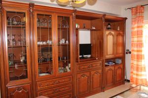 a large wooden cabinet with glass doors in a room at Grazioso appartamento vicino al mare in Giardini Naxos
