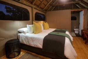 1 dormitorio con 1 cama grande con almohadas amarillas y verdes en Elephants Safari Lodge - Bellevue Forest Reserve en Paterson