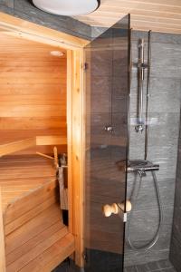 a shower in a tiny bathroom with wooden walls at Rahkis Lodge Saariselkä in Saariselka