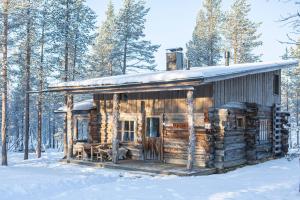 eine Blockhütte im Schnee mit Bäumen in der Unterkunft Rahkis Lodge Saariselkä in Saariselkä