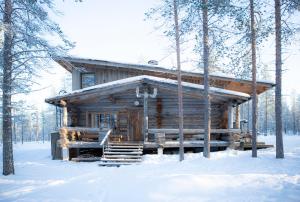 una cabaña de madera en el bosque en la nieve en Rahkis Lodge Saariselkä, en Saariselkä