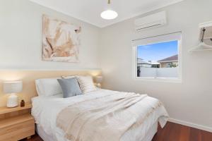 a white bedroom with a bed and a window at The Elements l Air l 4 Stunning Apartments each with Private Outdoor Dining l Walk to the Beach l Event Friendly l Wifi l Netflix l Outdoor Shower l Communal BBQ Pavilion and Lawn Area l in Christies Beach