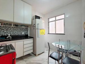 eine Küche mit einem Glastisch und einem Kühlschrank in der Unterkunft Europe Garden Apartment, 3 quartos in Juiz de Fora