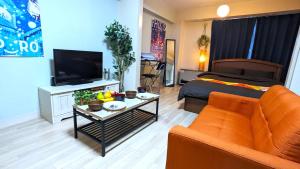 a living room with a bed and a couch and a tv at KIYAZA Space Sapporo in Sapporo