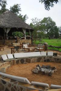 un groupe de chaises et de tables blanches et un bâtiment dans l'établissement Mikumi Wilderness Camp, à Kikoboga