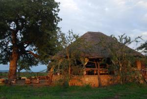 un edificio con techo de paja con un árbol en Mikumi Wilderness Camp, en Kikoboga