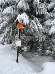 an orange sign in the snow next to some trees at Apartmán Plešivec ALL4FUN u sjezdovky in Abertamy