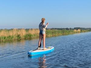 una mujer parada en una tabla de surf de remo en el agua en Boerencamping Swarthoeve, en Wormer