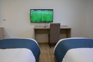 a room with two beds and a desk with a television at home in superior如家 in Surčin