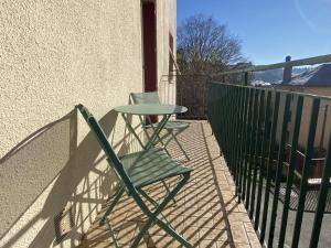 uma cadeira verde e uma mesa numa varanda em Le Fauvette em Rodez