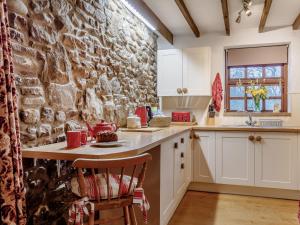 a kitchen with a stone wall and a table at 1 bed property in Gower 77981 in Penclawdd