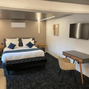 a hotel room with a bed and a desk and a table at Le Sainte Jeanne in Cormeilles-en-Vexin