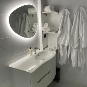 W białej łazience znajduje się umywalka i lustro. w obiekcie Le Sainte Jeanne w mieście Cormeilles-en-Vexin