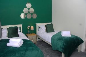 two beds in a room with green walls at Peedie Picky Townhoose - STL OR00094F in Orkney