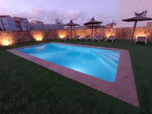 una piscina en un patio con sillas y luces en Casa El Rincón de Alberto con Calefacción y piscina, en Camelle