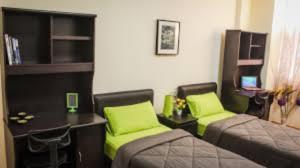 Habitación con 2 camas y escritorio con almohadas verdes. en Worker's Apartman-Munkásszálló, en Igricetanya